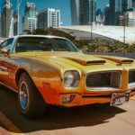 Yellow classic car front facing with a white top.