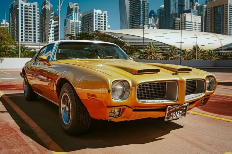 Yellow classic car front facing with a white top.