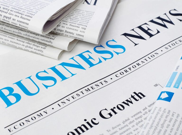 A picture of a business news paper with a few newspapers near.