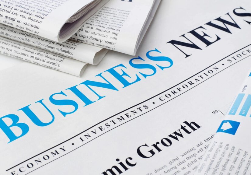 A picture of a business news paper with a few newspapers near.