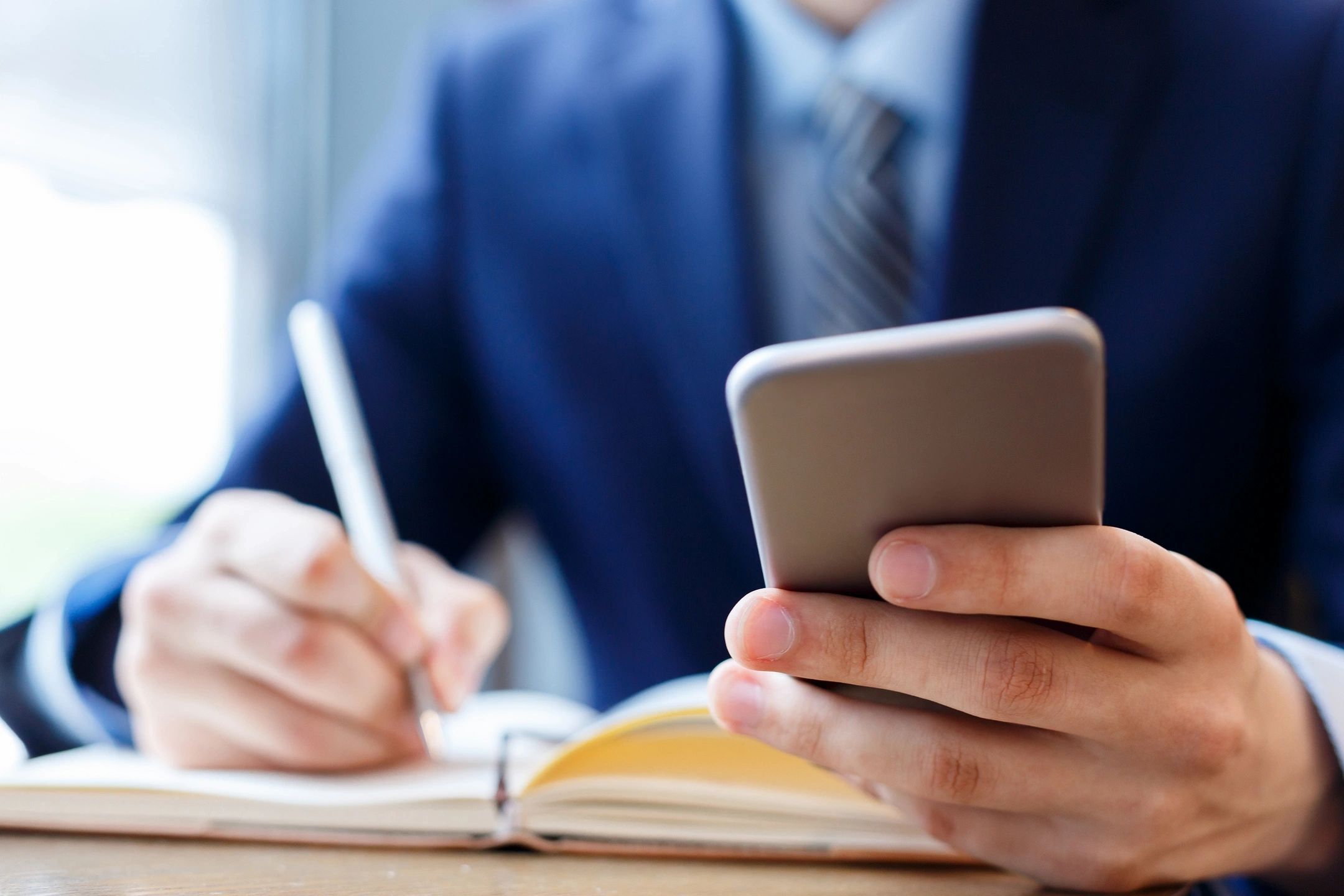 A male writing and using a calculator at the same time in an office setting.