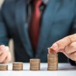 Man counting perfectly stacked coins with different heights.
