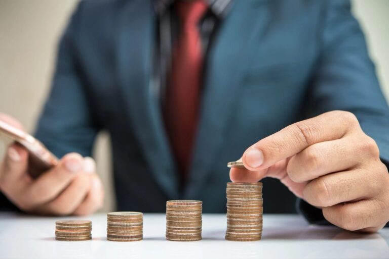 Man counting perfectly stacked coins with different heights.