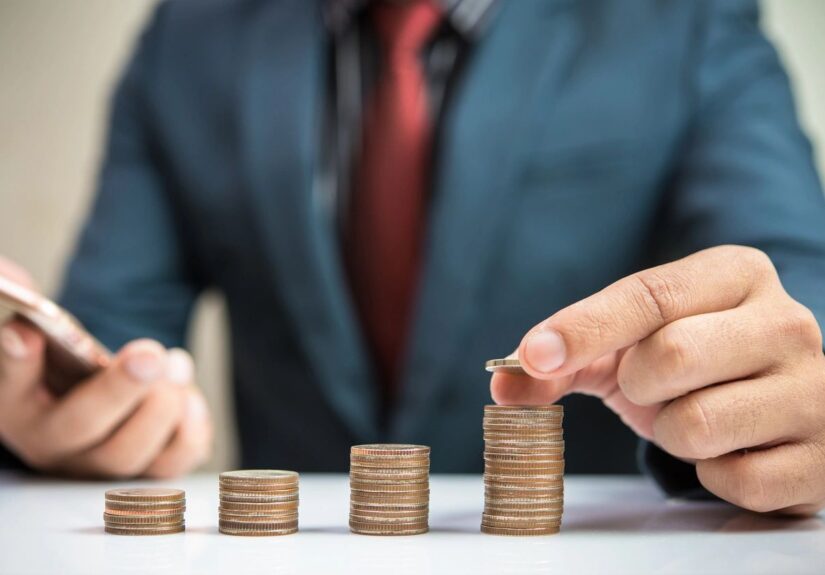 Man counting perfectly stacked coins with different heights.
