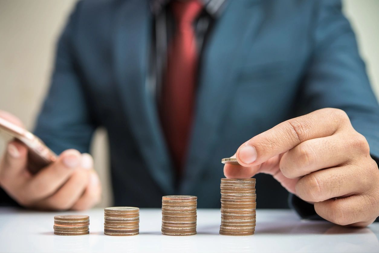 Man counting perfectly stacked coins with different heights.