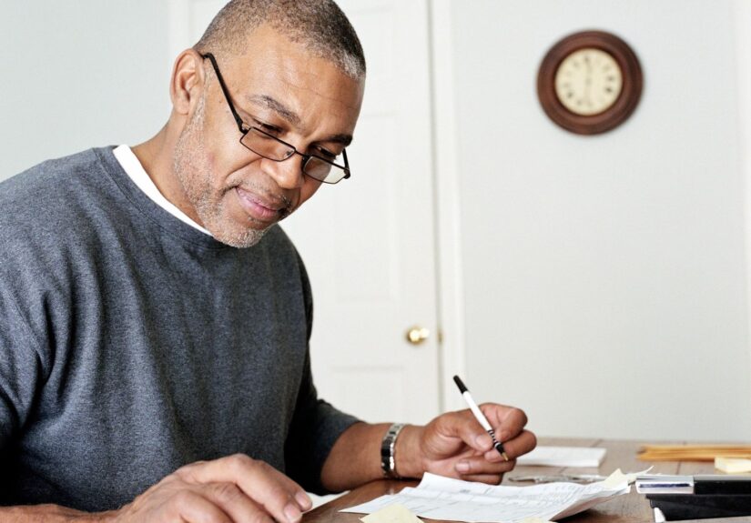A man working on his finances with a calculator and a pen in hand.