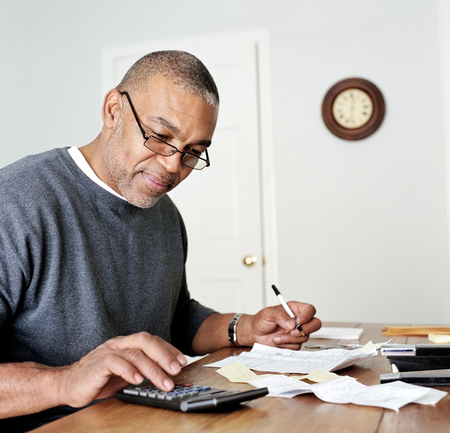 A man working on his finances with a calculator and a pen in hand.
